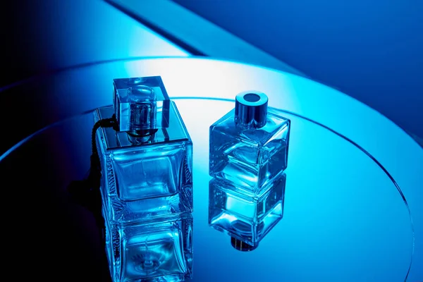 Blaue Parfümflaschen mit Reflexion auf runder Spiegeloberfläche — Stockfoto