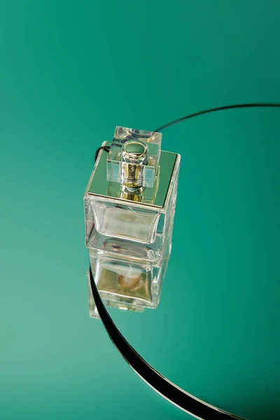 Frasco de perfume de vidro na superfície do espelho verde redondo — Fotografia de Stock