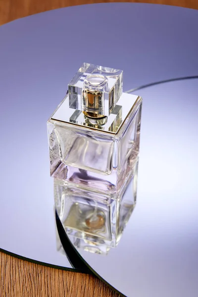 Glass perfume bottle on round violet mirror surface — Stock Photo