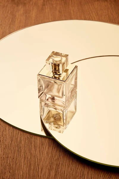 Скляна пляшка парфумів на круглому бежевому дзеркалі — стокове фото