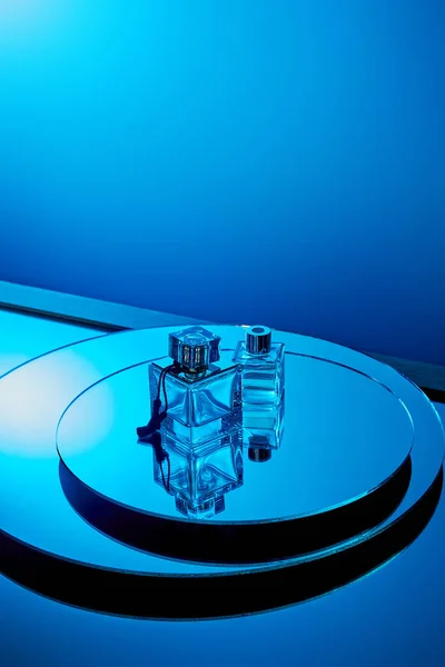 High angle view of blue perfume bottles on round mirror surface — Stock Photo