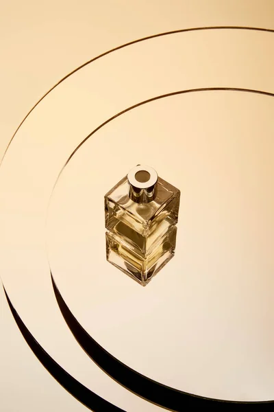 High angle view of golden perfume bottle on round mirror surface with reflection — Stock Photo