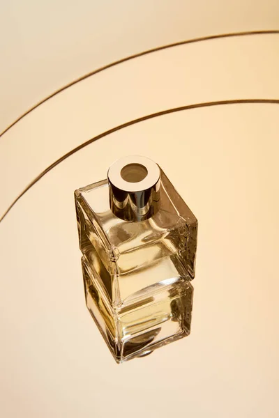 Vista de ángulo alto de la botella de perfume en la superficie redonda espejo beige con reflexión - foto de stock