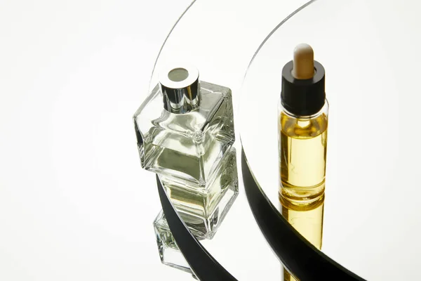 Vista de alto ângulo do frasco de perfume e do frasco de soro na superfície do espelho — Fotografia de Stock