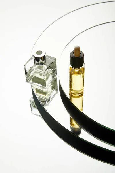 High angle view of luxury perfume bottle and serum bottle on mirror surface — Stock Photo