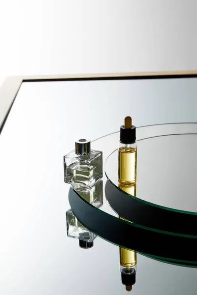 High angle view of perfume bottle and serum bottle on mirror surface — Stock Photo