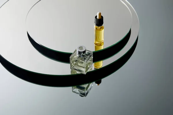 Vista de alto ângulo do frasco de perfume e do frasco de soro na superfície do espelho — Fotografia de Stock