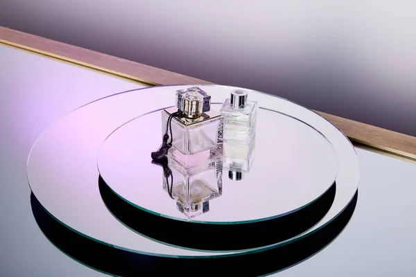 Vue grand angle des bouteilles de parfum violet de luxe sur la surface du miroir rond — Photo de stock