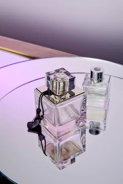 Vista de alto ângulo de frascos de perfume roxo na superfície do espelho redondo violeta — Fotografia de Stock