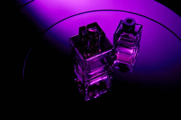 Vue grand angle des flacons de parfum violet sur la surface miroir violet rond — Photo de stock