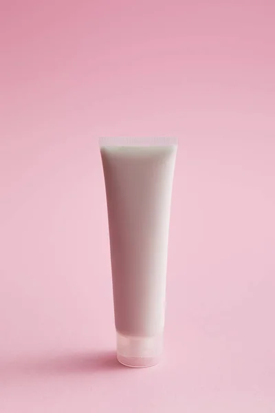 Plastic cosmetic cream tube on pink background — Stock Photo