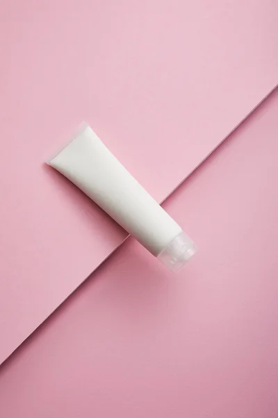 Vista superior del tubo de crema cosmética sobre fondo rosa - foto de stock