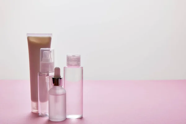 Conjunto de cosméticos de cuidados com a pele sobre fundo rosa e cinza — Fotografia de Stock