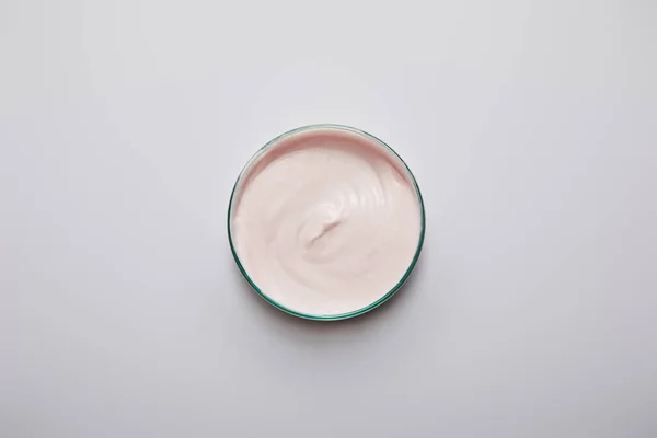 Vista superior de artigos de vidro de laboratório com creme cosmético rosa sobre fundo cinza — Fotografia de Stock