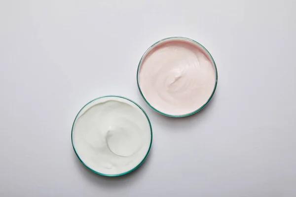 Vista superior de artigos de vidro de laboratório com creme cosmético branco e rosa sobre fundo cinza — Fotografia de Stock