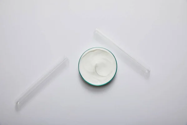 Draufsicht auf Laborgläser mit weißer Kosmetikcreme und Reagenzgläsern auf grauem Hintergrund — Stockfoto