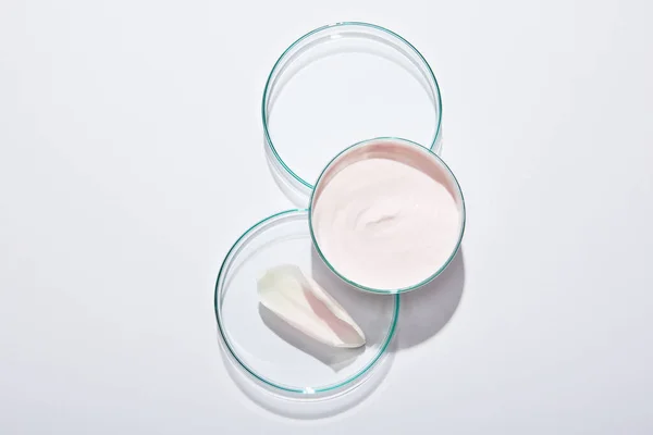 Vue du dessus de la verrerie de laboratoire avec crème cosmétique rose et pétale de rose sur fond gris — Photo de stock