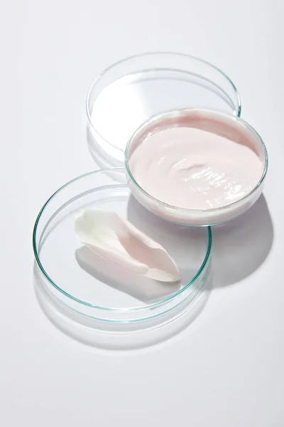 Vue grand angle de la verrerie de laboratoire avec crème cosmétique et pétale de rose sur fond gris — Photo de stock