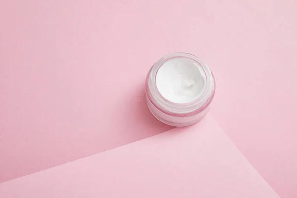 Creme cosmético em frasco de vidro sobre fundo rosa — Fotografia de Stock