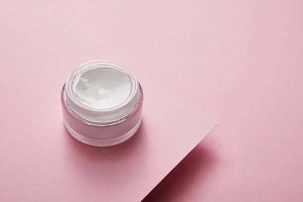 Vue grand angle de la crème cosmétique en pot de verre sur fond de papier rose — Photo de stock