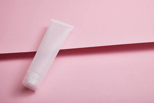 Vista ad alto angolo di vuoto tubo crema cosmetica plastica su sfondo rosa strutturato — Foto stock