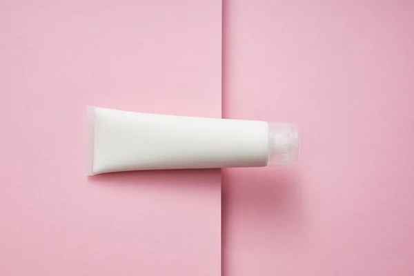 Vue du dessus du tube en plastique avec crème cosmétique blanche sur fond rose — Photo de stock