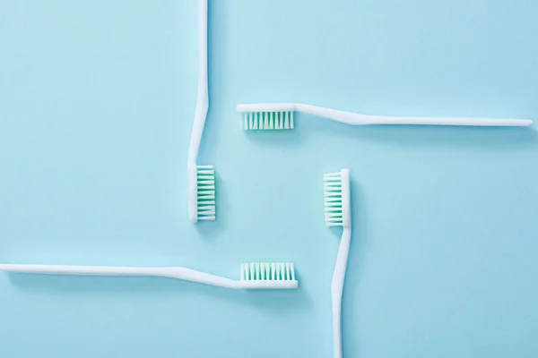 Acostado plano con cepillos de dientes establecidos sobre fondo azul - foto de stock