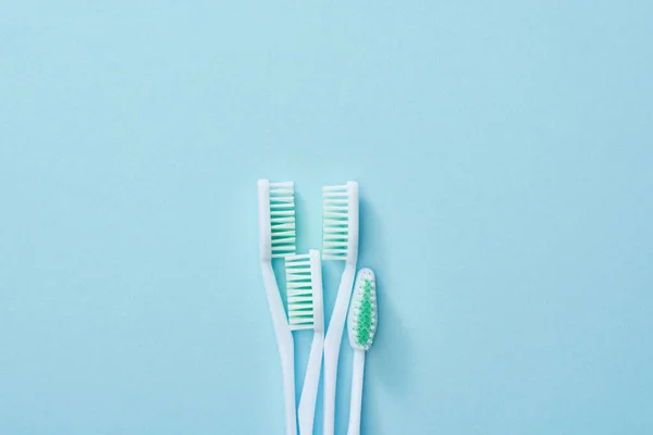 Vue du dessus des brosses à dents blanches à poils verts sur fond bleu — Photo de stock