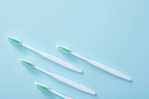 Pose plate avec brosses à dents avec soies vertes sur fond bleu — Photo de stock