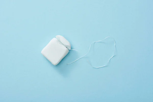 Top view of white dental floss on blue background — Stock Photo