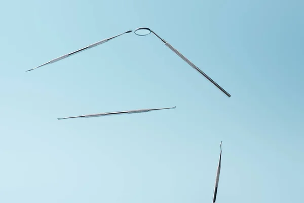 Instrumentos dentários metálicos levitando isolados sobre fundo azul — Fotografia de Stock