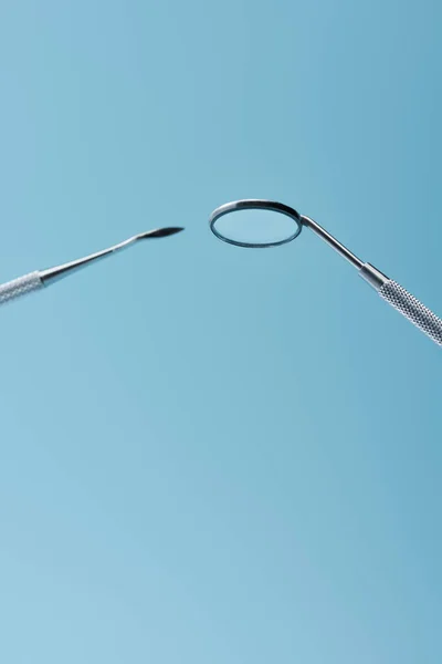 Instrumentos de examen dental de metal aislados sobre fondo azul - foto de stock