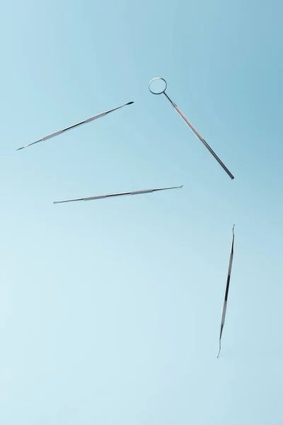 Instrumentos de examen dental instrumentos que levitan sobre fondo azul - foto de stock