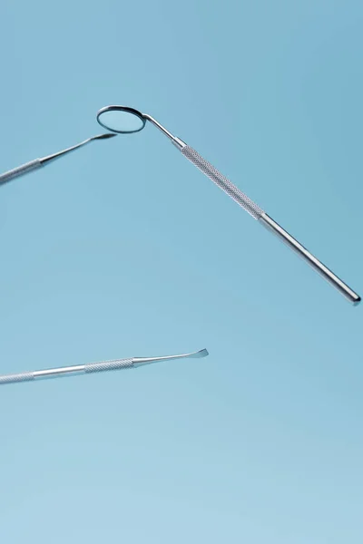 Instrumentos profesionales dentales metálicos levitando aislados sobre fondo azul - foto de stock