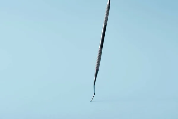 Escalador dental profesional de metal sobre fondo azul - foto de stock