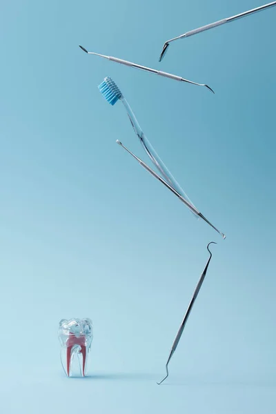 Dental instruments, toothbrush and artificial plastic tooth on blue background — Stock Photo