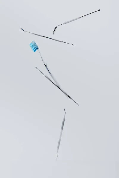 Dental instrumens and toothbrush levitating on grey background — Stock Photo