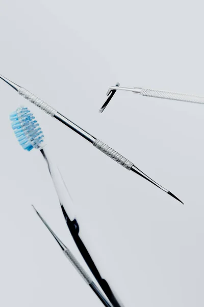 Dental instruments and toothbrush with blue bristles isolated on grey background — Stock Photo