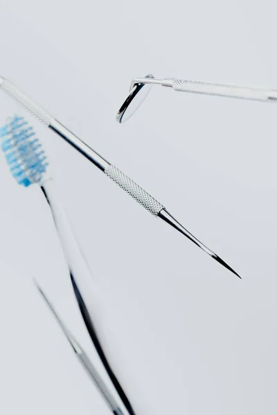 Focus selettivo di attrezzature dentali professionali e spazzolino da denti con setole blu isolate su sfondo grigio — Foto stock