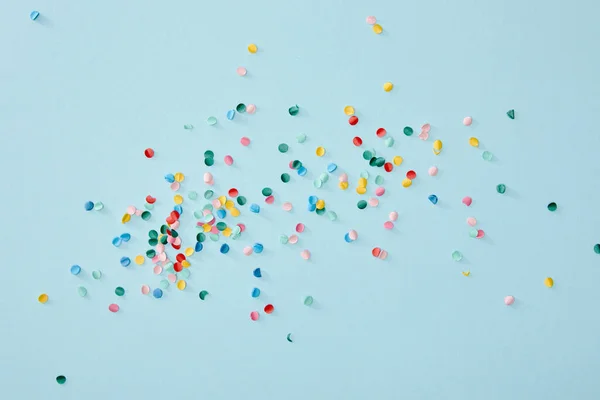 Vista superior de confetes coloridos espalhados no fundo azul — Fotografia de Stock
