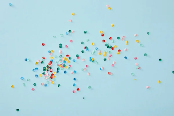 Vue de dessus de confettis colorés dispersés sur fond bleu — Photo de stock