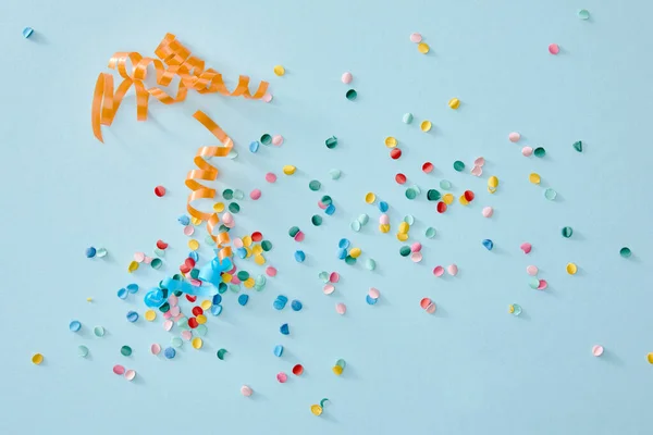 Вид зверху барвистий конфетті, розкиданий на синьому фоні — стокове фото