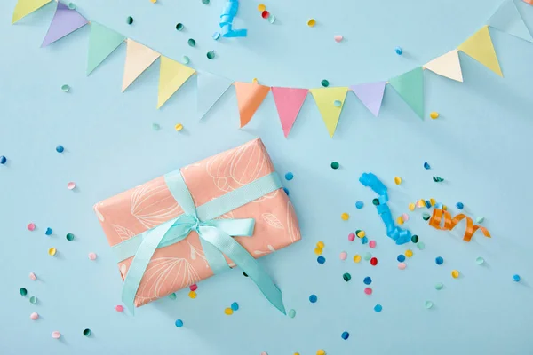 Vista superior de confeti colorido cerca de caja de regalo sobre fondo azul - foto de stock