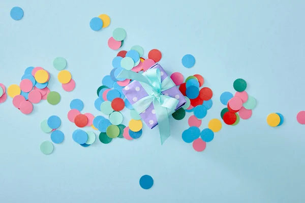 Top view of colorful confetti near present on blue background — Stock Photo
