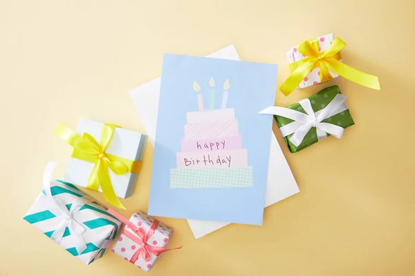 Top view of festive colorful gifts and happy birthday greeting card on beige background — Stock Photo