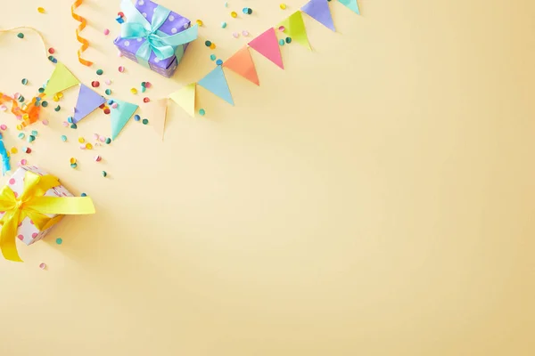Vista superior de confeti colorido festivo y cajas de regalo sobre fondo beige - foto de stock