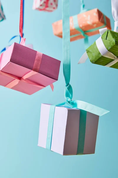 Selektiver Fokus von festlich bunten Geschenkboxen, die an Bändern auf blau isoliert hängen — Stockfoto