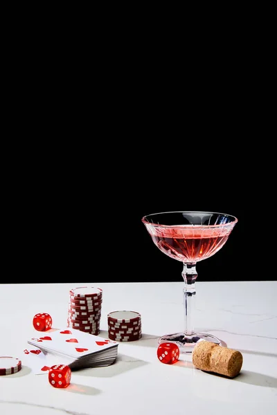 Deck of cards, glass of cocktail, dice, casino tokens and cork on white surface isolated on black — Stock Photo