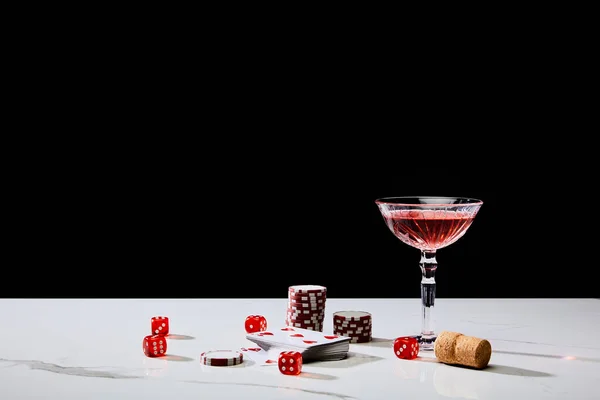 Pack of cards, glass of cocktail, dice, casino tokens and cork on white surface isolated on black — Stock Photo