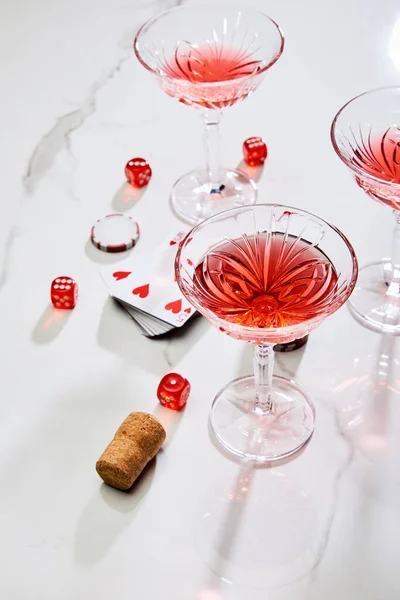 High angle view of deck of cards, glasses of cocktail, dice, casino token and cork on white background — Stock Photo